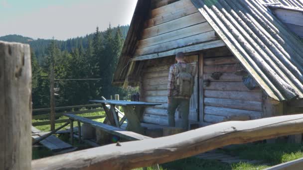 バックパックを持った男がドアを開け 古い木造の家に入る 山中のカルパティアの羊飼いの本当の家 旅行と街からの脱出の概念 スローモーション映像 — ストック動画