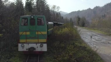 Aerial view of the train rides on the railroad. Drone flight over the locomotive and carriages of the narrow gauge railway.