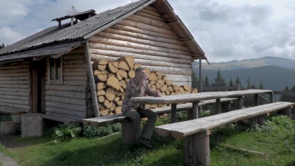 Bir Adam Dağlarda Eski Bir Ahşap Evin Yanında Dinleniyor Dağlardaki — Stok video