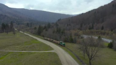 Eski dar bir demiryolu boyunca kereste taşıyan bir yük treninin havadan görünüşü. Karpatlar, Ukrayna 'da odun toplama endüstrisi