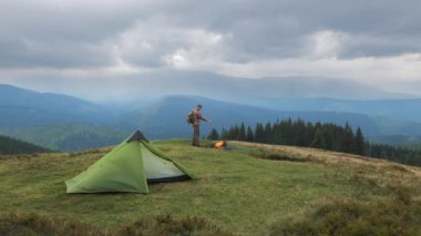 Sırt çantalı bir adam, dağlarda ateşin yanında. Camp Life, şehirden kaçmak. Macera kavramı, seyahat. Yavaş çekim 4K