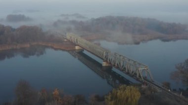 Sabahın erken saatlerinde, nehrin üzerindeki demiryolu köprüsünün sisli görüntüsü.