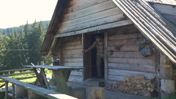 旅人は古い木造の家を出ていく 山中のカルパティアの羊飼いの本当の家 アドベンチャー 街からの脱出の概念 スローモーション映像 — ストック動画