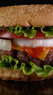 Taze iştah açıcı sığır Burger dönüyor. Lezzetli burger, taze lahana, soğan, domates ve ızgara biftek. Döndürme - fast food, yakın çekim, dikey görüntü