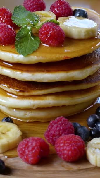 美味的早餐食物 煎饼与覆盆子 蓝莓和薄荷叶一起食用 旋转的特写镜头 垂直镜头 — 图库视频影像