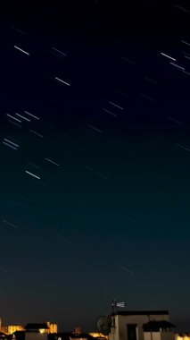 Gece gökyüzünde yıldızın zaman aralıkları şehrin üzerinde, dikey görüntüler