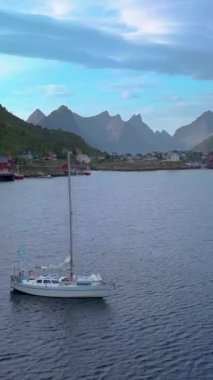 Norveç, Hamnoy 'da küçük bir balıkçı köyünün yakınındaki deniz koyundaki yat üzerinde uçuş. Lofoten adaları güzel fiyortları, dağları ve Norveç doğası ile ünlüdür.