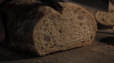 Ev yapımı sert çavdar ekmeğini tahta tahtada keskin bir bıçakla kesiyor, yavaş çekimde kesiyor.