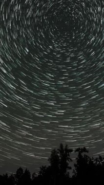 Gece gökyüzünde Yıldız 'ın zaman atlaması. Yıldızlar bir kutup yıldızının etrafında döner. Destansı video, dikey görüntü
