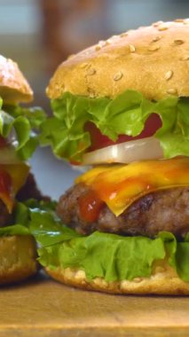 Taze domates, soğan, sulu ızgara sığır eti ve peynirli büyük iştah açıcı hamburgerler. Fast food, yakın çekim, dikey çekim