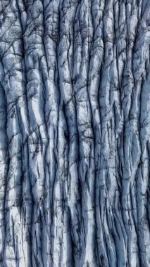 Aerial View, İzlanda 'daki bir Svinafellsjokull Buzulu üzerindeki derin yarıkların ve dokulu buzun karmaşık örüntülerini ortaya çıkarır. Dikey görüntüler
