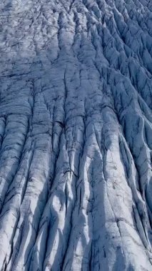 Aerial View, İzlanda 'daki bir Svinafellsjokull Buzulu üzerindeki derin yarıkların ve dokulu buzun karmaşık örüntülerini ortaya çıkarır. Dikey görüntüler
