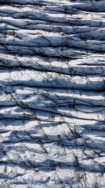 Aerial View, İzlanda 'daki bir Svinafellsjokull Buzulu üzerindeki derin yarıkların ve dokulu buzun karmaşık örüntülerini ortaya çıkarır. Dikey görüntüler