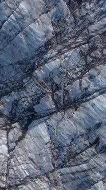 Aerial View, İzlanda 'daki bir Svinafellsjokull Buzulu üzerindeki derin yarıkların ve dokulu buzun karmaşık örüntülerini ortaya çıkarır. Dikey görüntüler
