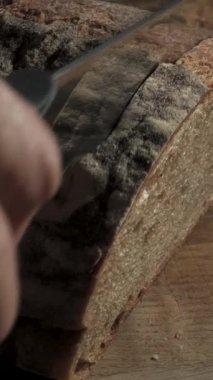 Ev yapımı çavdar ekmeği dilimlemek tahta tahtada keskin bir bıçakla yakın plan dikey görüntüler.