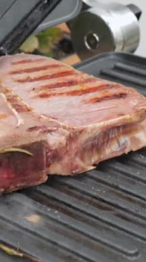 Biberiyeli lezzetli biftek elektrikli ızgarada pişirilir. Yıllanmış az pişmiş ızgara sığır filetosu taze mermer hassasiyet bifteği. Elektrikli kızartma makinesinde kızarmış et. dikey görüntüler