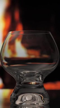 Şöminenin arkasından viski ya da konyak şişeden bardağa dökülüyor. Sıcaklık ve ev konforu. dikey görüntüler