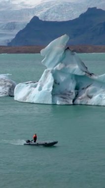 Jokulsarlon, İzlanda 'da eriyen bir buzul gölünde yüzen bir tekne. dikey görüntüler