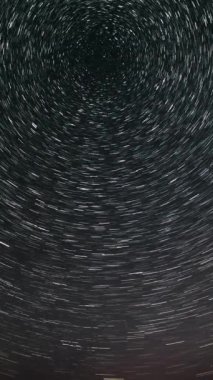 Gece gökyüzünde Yıldız 'ın zaman atlaması. Yıldızlar bir kutup yıldızının etrafında döner. Destansı video, dikey görüntü