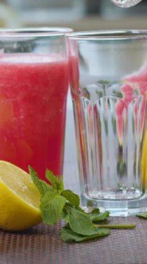 Taze meyvelerin arka planındaki bir bardağa karpuz muzlu meyve suyu dökülüyor. Meyve kokteyli yemek için hazır. Sağlıklı ve vejetaryen gıda konsepti. dikey görüntüler