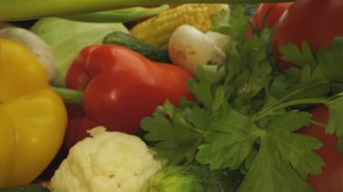 Markette taze sebzelerin yakın plan çekimi. Kırmızı dolma biber, sarı dolma biber, karnabahar, yeşil soğan, mısır, mantar ve maydanoz hepsi görünür..