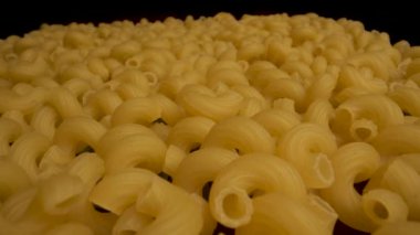 Yakın plan pişmemiş cavatappi makarnası. Makarna soluk sarı renktedir ve spiral bir şekli vardır..
