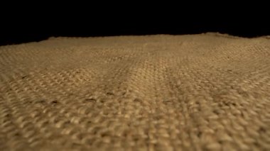 Bu video, çuval bezi kumaşının dokusunu yakından görüntüler. Kamera yavaşça yüzey boyunca döner ve doğal liflerin karmaşık dokuma kalıbını ortaya çıkarır..