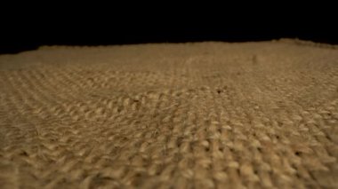 Bu video, çuval bezi kumaşının dokusunu yakından görüntüler. Kamera yavaşça yüzey boyunca döner ve doğal liflerin karmaşık dokuma kalıbını ortaya çıkarır..