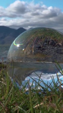 Deniz ve dağlar camdan bir topun içinden bakıyorlar. İzlanda. dikey video