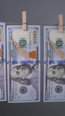 Yüzlerce dolarlık banknotlar kapalı bir alanda kazara yıkandıktan sonra kuruyor. Güneş ışığı, alışılmadık bir durumu gösteren canlı detayları ve canlı renkleri vurguluyor..