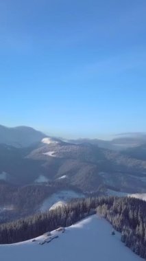 Manzara, berrak mavi bir gökyüzü altında yuvarlanan karla kaplı dağları yakalar ve sakin doğal bir manzaranın güzelliğini gözler önüne serer. Dikey görüntüler