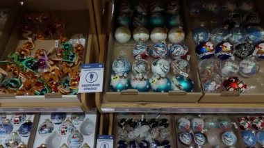 KYIV, UKRAINE - 22 Aralık 2024: Bir mağazadaki raflarda çeşitli dekoratif süsler düzenlenmiştir, canlı renkler ve bayram sezonunu kutlayan şenlikli tasarımlar sergilenmektedir.