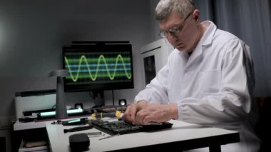 Beyaz laboratuvar önlüklü bir teknisyen, devre kartında özenle çalışır. Araçlar düzgünce düzenlenmiş olarak arkaplanda dalga biçimleri gösterilir.
