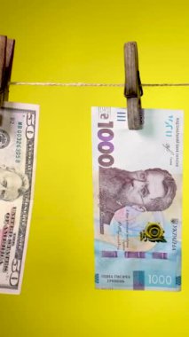 Farklı ülkelerin banknotları sarı arka planda çamaşır iğnesi ipiyle kurur. Para aklama konsepti. Dikey görüntüler