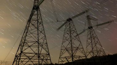Uzun pozlama fotoğrafçılığı, yıldızların kırsal alandaki yüksek enerji hatlarının üzerindeki hareketlerini vurgular ve doğa ile insan mühendisliği arasındaki zıtlığı gösterir..