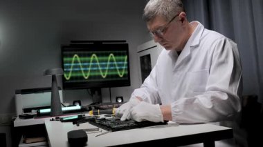 Bir teknisyen, iyi donanımlı bir laboratuvardaki devre kartında özenle çalışır. Bir monitör, elektronik onarımının hassasiyetini vurgulayan bir dalga biçimi gösterir.
