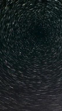 Gece gökyüzünde Yıldız 'ın zaman atlaması. Yıldızlar bir kutup yıldızının etrafında döner. Destansı video, dikey görüntü