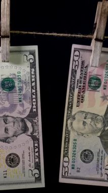 Siyah arka planda çamaşır iğnesi ipinde dolar kurur. Dolar 'ın finansal konsepti. Para aklama konsepti. Dikey görüntüler