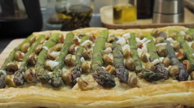 Yeşil zeytinli kuşkonmaz turtası ve puf böreği üzerine peynir, yakın plan fırında pişmiş lezzetli tart. Üstünde yeşil kuşkonmaz mızrakları var.