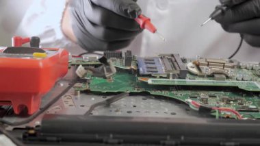 Anakart, sonda ve çokölçer ile test ediliyor, elektronik tanılama sırasında bilgisayar ana kartında sonda kullanan teknisyenlerin yakın çekimi