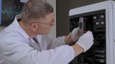 Alet ve eldivenlerle bilgisayar donanımını tamir eden teknisyen, laboratuvar önlüklü mühendis hassas iç bilgisayar parçaları üzerinde çalışıyor.