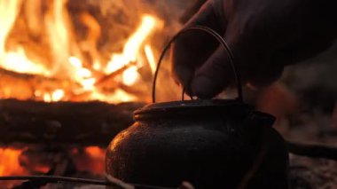 Kırsal bir siyah çaydanlık, parlayan közlerle çevrili açık bir ateşin üzerinde ısınır. Vahşi doğada mükemmel bir hayatta kalma ve çalılık sahnesi..