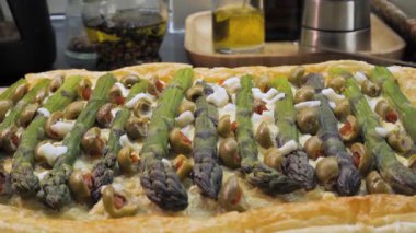 Yeşil zeytinli kuşkonmaz turtası ve puf böreği üzerine peynir, yakın plan fırında pişmiş lezzetli tart. Üstünde yeşil kuşkonmaz mızrakları var.