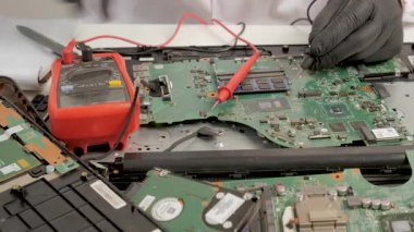 Ana kart bileşenlerini Multimetre ile ölçen teknisyen, ana kart devrelerini test etmek için çoklu metre kullanıyor..