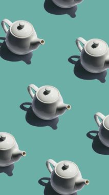 Turkuaz arka planda pürüzsüz çaydanlık deseni sert gölgeli, beyaz seramik çaydanlıklar güçlü gölgeler ve dikey görüntülerle donatılmış bir deniz mavisi arkaplanı boyunca tekrarlanıyor.