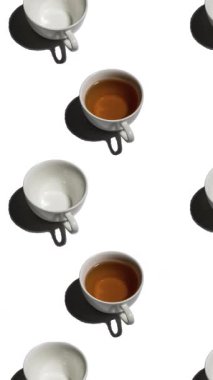 Beyaz arka planda bir sürü çay fincanı ve boş fincanı olan desen. Sıcak içecekli çay fincanları farklı yönlere hareket eder. dikey görüntüler