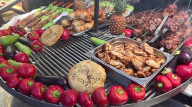 Grilled meats with colorful vegetables on open barbecue, Juicy skewers, baked bread and roasted chicken wings with fresh produce accents