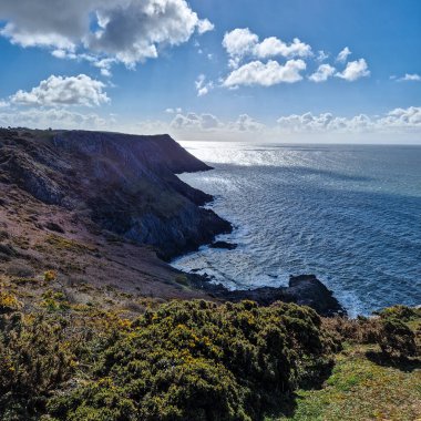 Arka planda görünen üç uçurum keskin açıları ve engebeli dokularıyla sahneye dram katıyor. Körfezin sakin ve berrak suları sörf, yüzme ya da huzurlu bir günün tadını çıkarmak için mükemmel bir zemin sağlar.