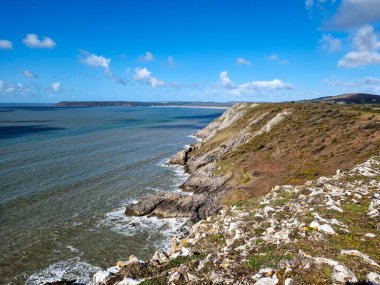 Arka planda görünen üç uçurum keskin açıları ve engebeli dokularıyla sahneye dram katıyor. Körfezin sakin ve berrak suları sörf, yüzme ya da huzurlu bir günün tadını çıkarmak için mükemmel bir zemin sağlar.