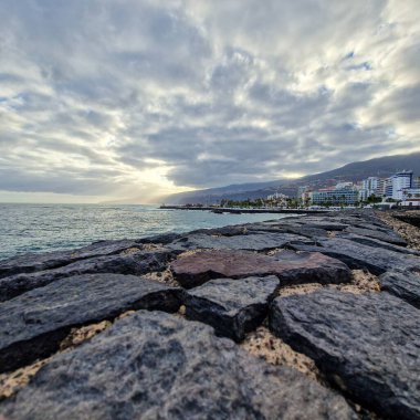 Şafak sökerken, Puerto de la Cruz sabah güneşinin yumuşak kucaklamasına uyanır. Şehir, hala gecenin kalıntılarıyla sarılı, ışığın ilk ışıklarıyla parıldamaya başlıyor. Sokaklar, binalar ve sular S 'nin yumuşak pastel tonlarını yansıtıyor.